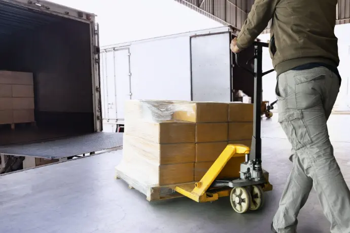 Warehouse worker loading a a shipment of good into a cargo freight truck